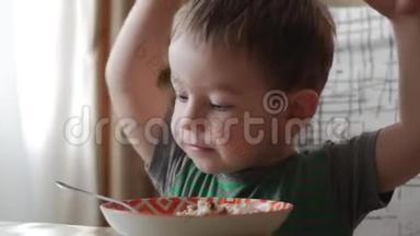可爱的小<strong>宝宝</strong>一个人用勺子从盘子里吃粥，健康<strong>饮食</strong>的概念。